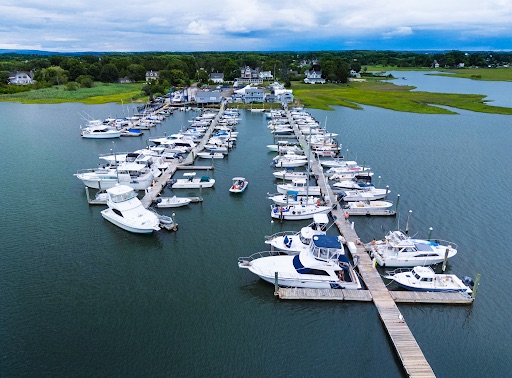 Drone view of Petzold’s Port Clinton Marina with boats, docks, waterfront buildings and surrounding coastal marshland in Clinton, Connecticut.