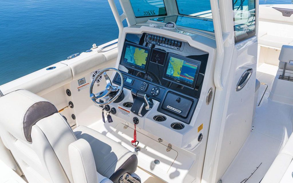 The open helm station of a Sailfish 272 center console, its white gelcoat and vinyl seating exposed to sun and salt air