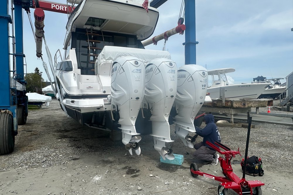 A technician servicing a boat’s outboard engines in the marina yard
