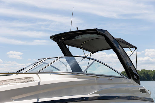 A boat moored on calm water at the marina with its hardtop and bimini canopy raised.
