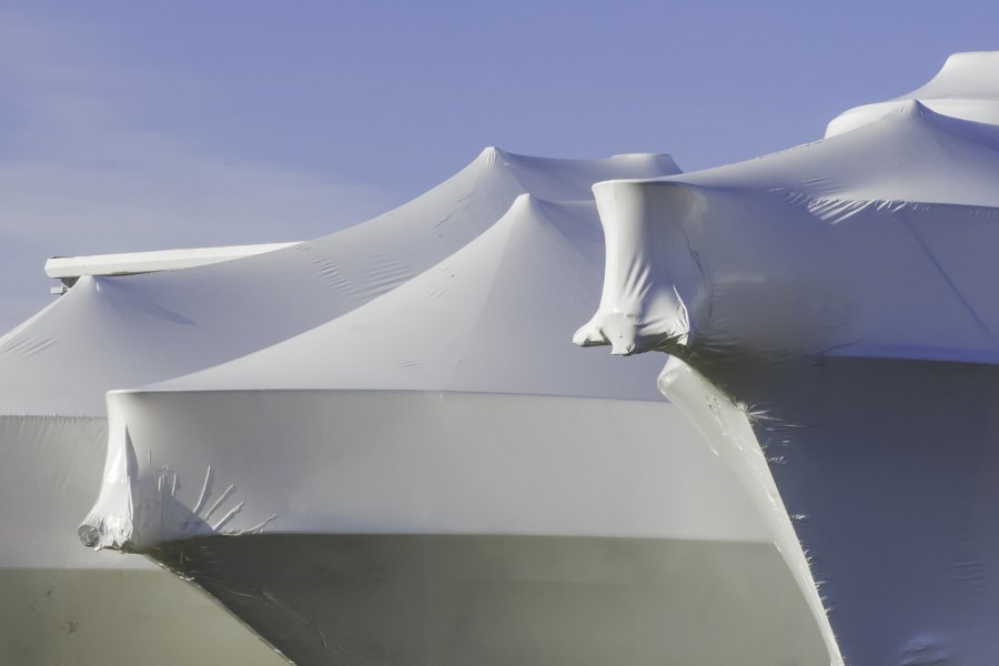 Boats shrink-wrapped in white plastic for outdoor winter storage